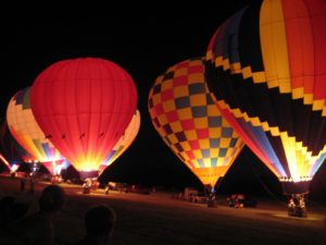 A group of hot air balloons lit up at night.